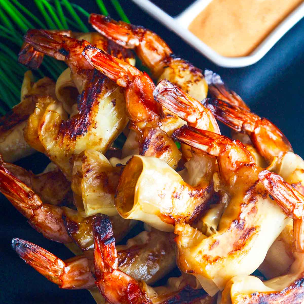 A firecracker shrimp recipe with two dipping sauces on a black platter.