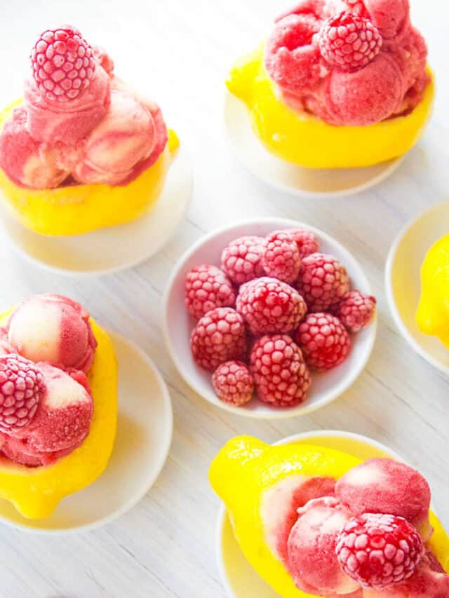 Bright yellow lemons carved out and filled with raspberry strawberry lemon sorbet as a summer dessert.