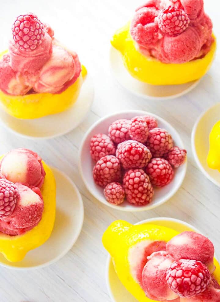 Bright yellow lemons carved out and filled with raspberry strawberry lemon sorbet as a summer dessert.