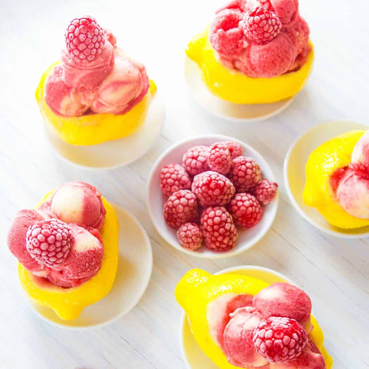 Bright yellow lemons carved out and filled with raspberry strawberry lemon sorbet as a summer dessert.
