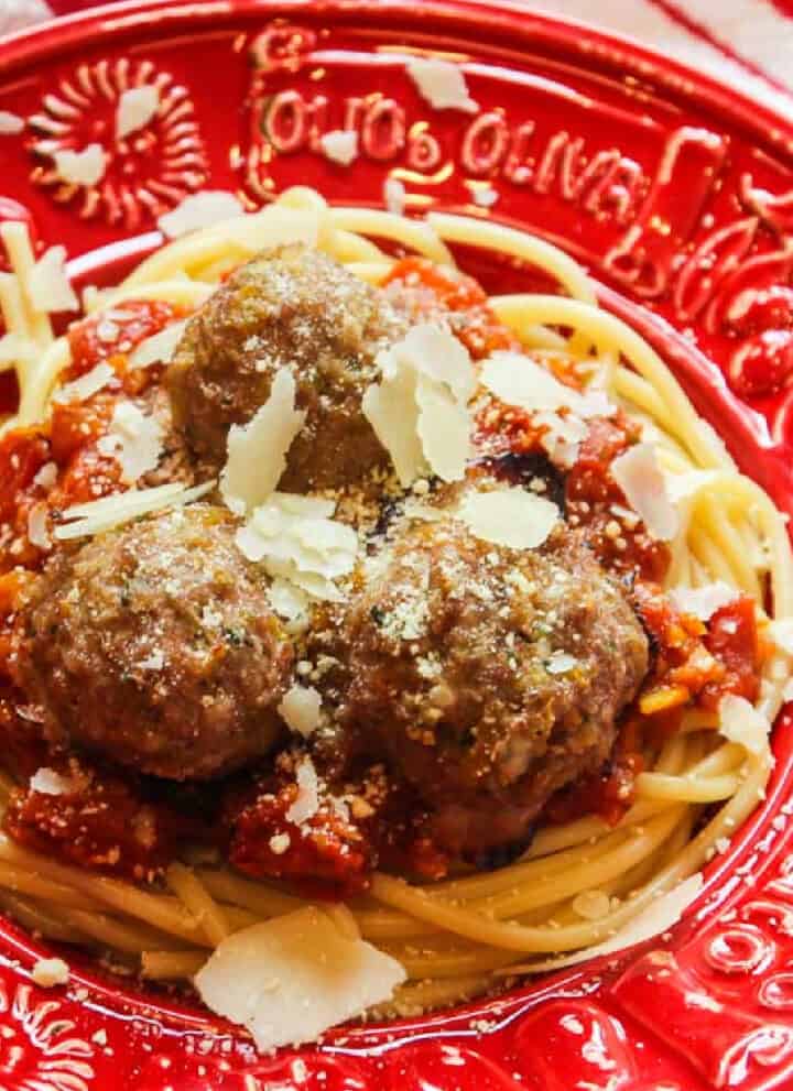 A red Italian bowl with hot pasta, sauce and turkey meatballs topped with shaved parmesan cheese.