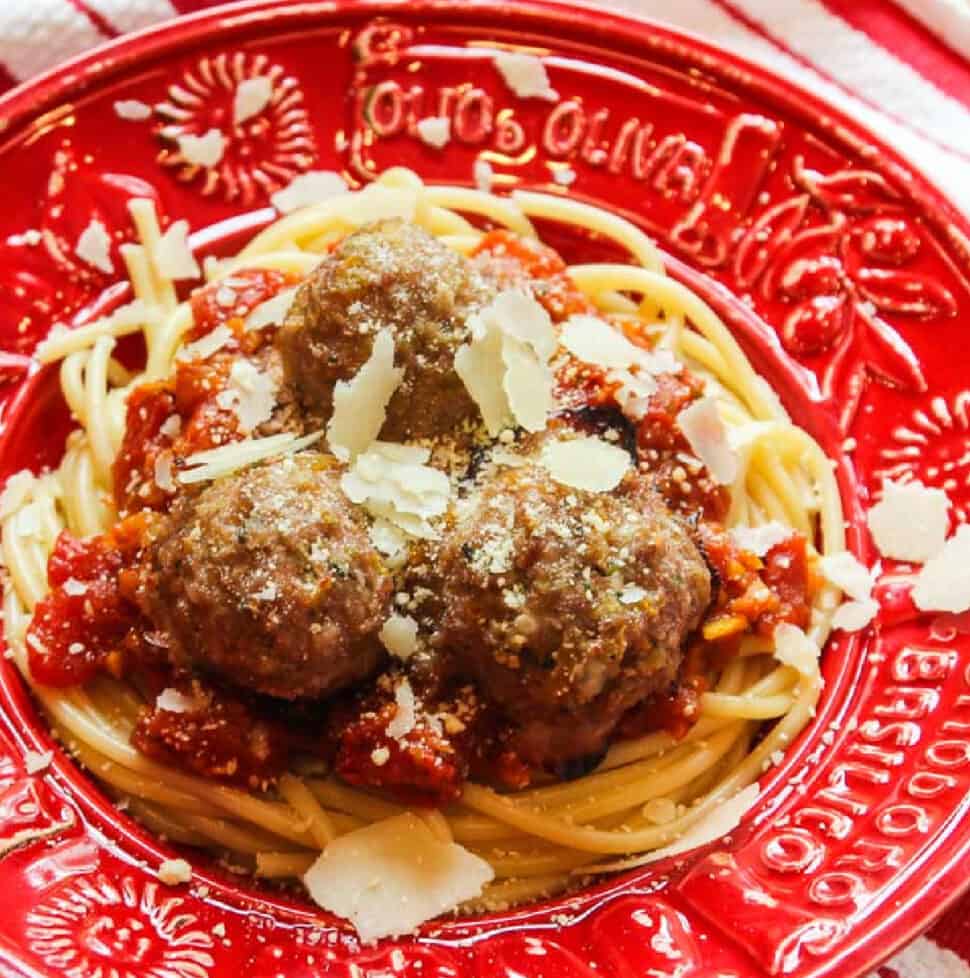 A red Italian bowl with hot pasta, sauce and turkey meatballs topped with shaved parmesan cheese.