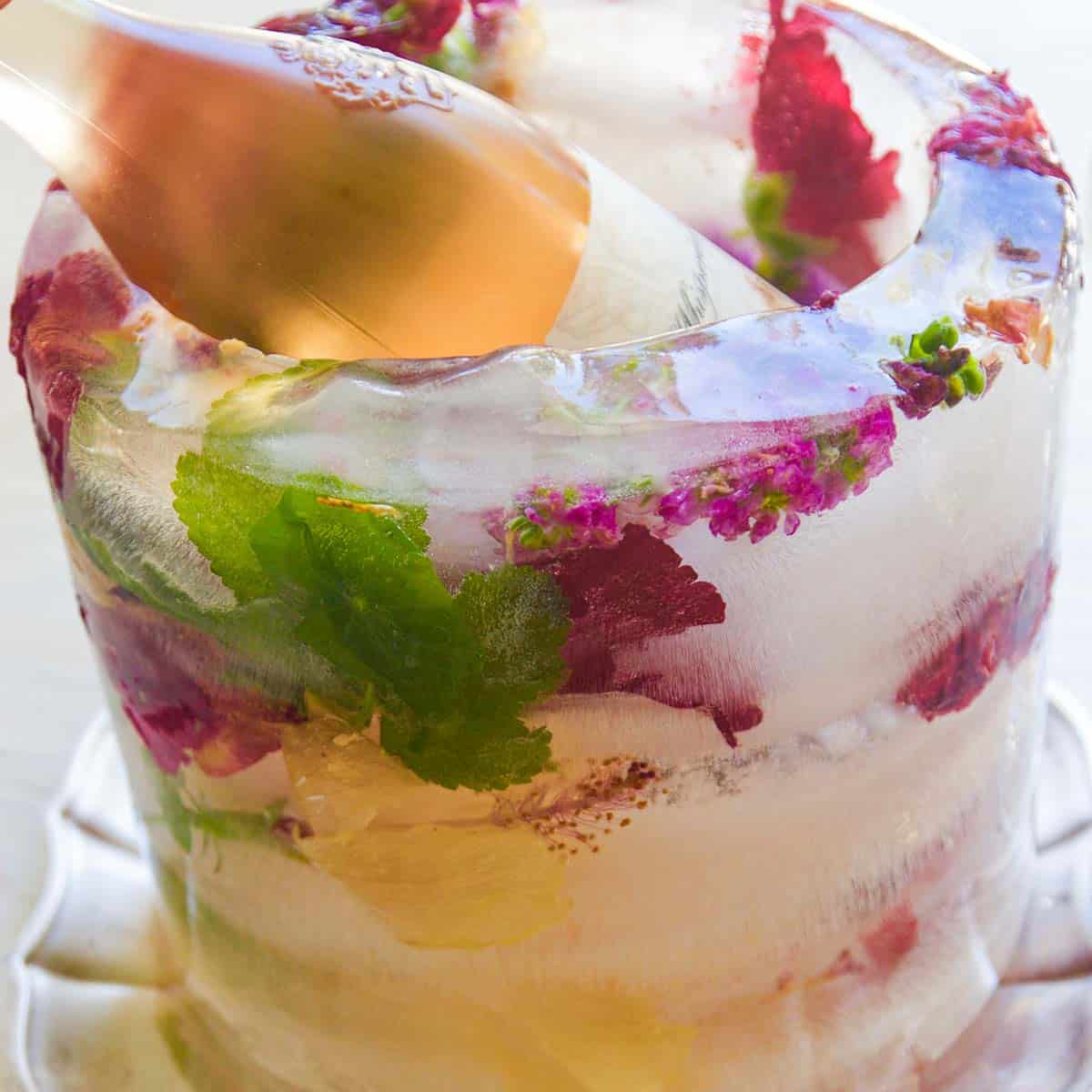 The side of a frozen floral ice bucket with pink and purple flowers and a bottle of wine inside chilling.