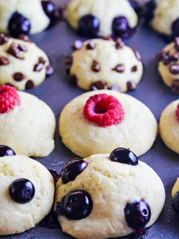 Baked pancake muffins in a tin topped with blueberries, mini chocolate chips, and raspberries.