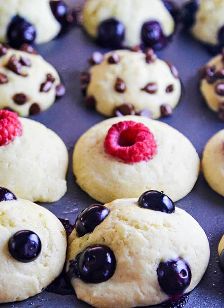 Baked pancake muffins in a tin topped with blueberries, mini chocolate chips, and raspberries.