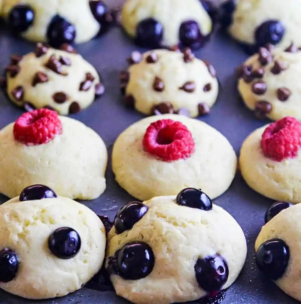 Baked pancake muffins in a tin topped with blueberries, mini chocolate chips, and raspberries.