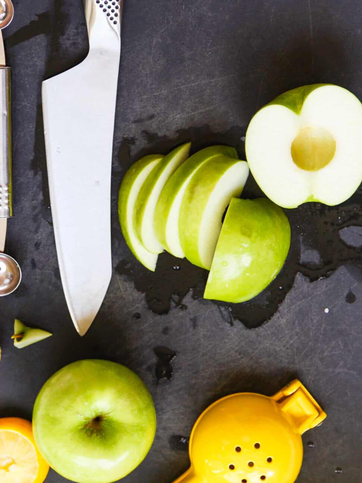 A cutting board and knife cutting apples for caramel apple dip.