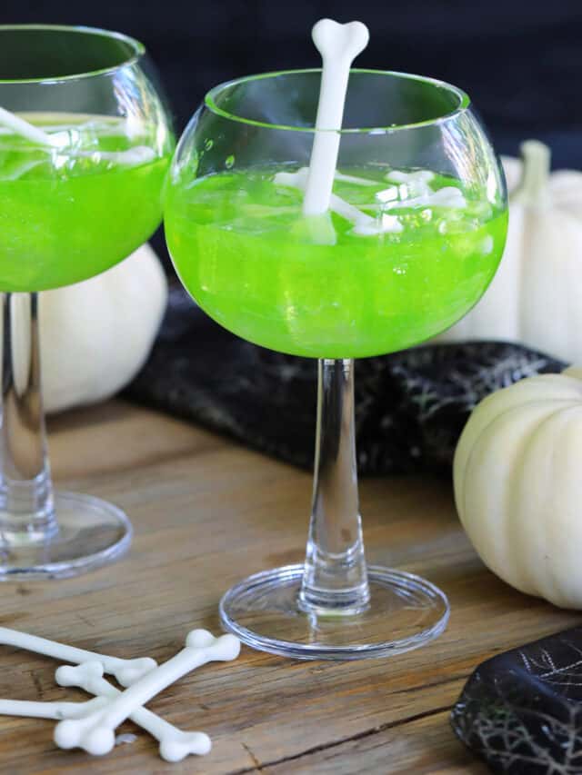 A Halloween party with two green cocktails using Midori and garnished the Witches brew midori sours are garnished with white plastic bones for Halloween cocktails.