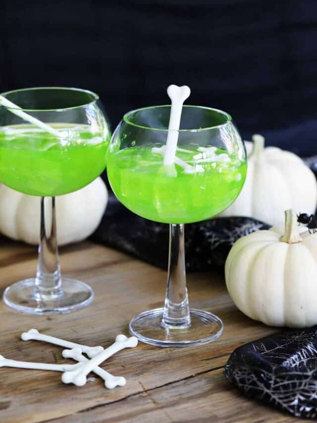 A Halloween party with two green cocktails using Midori and garnished the Witches brew midori sours are garnished with white plastic bones for Halloween cocktails.