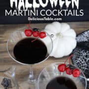 Two Halloween black drinks make with black vodka garnished with 3 red maraschino cherries and a black spider.