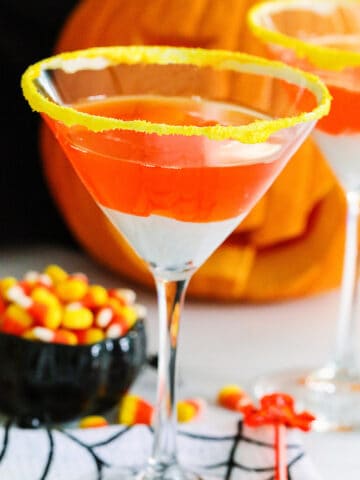 A Halloween party with candy corn martinis and a small black dish of candy corn nearby.