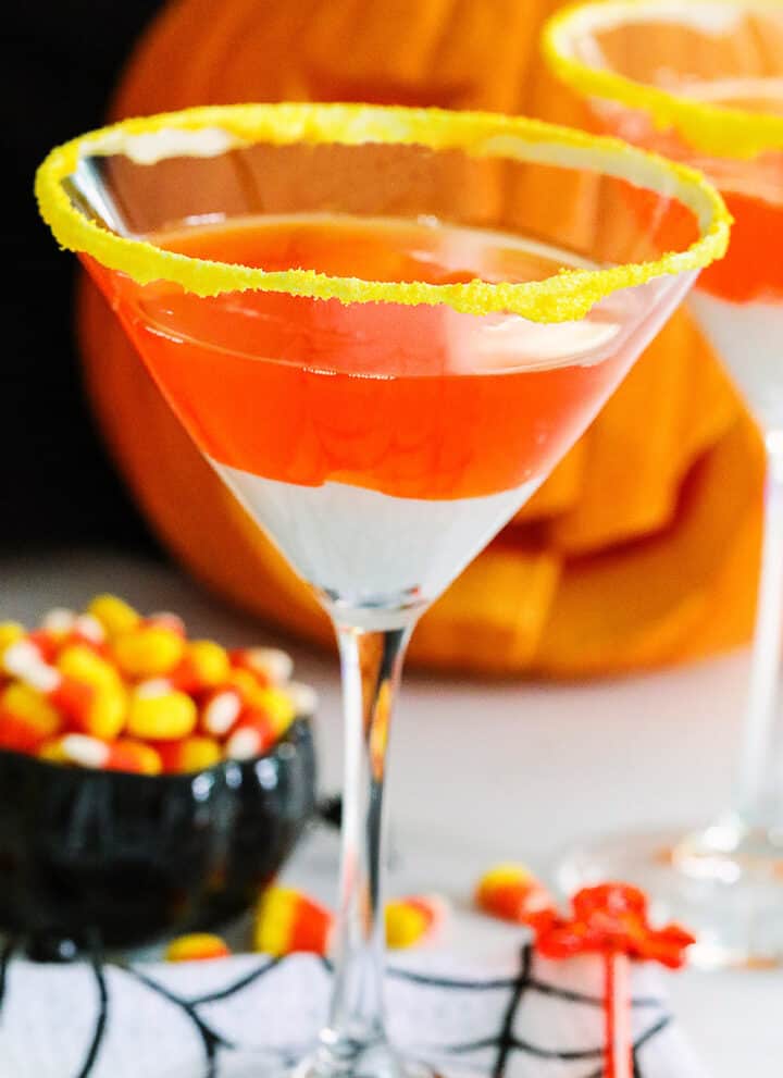 A Halloween party with candy corn martinis and a small black dish of candy corn nearby.