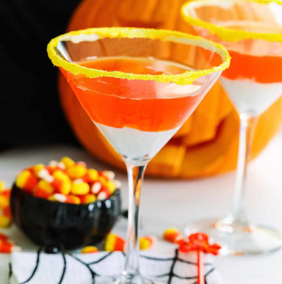 A Halloween party with candy corn martinis and a small black dish of candy corn nearby.