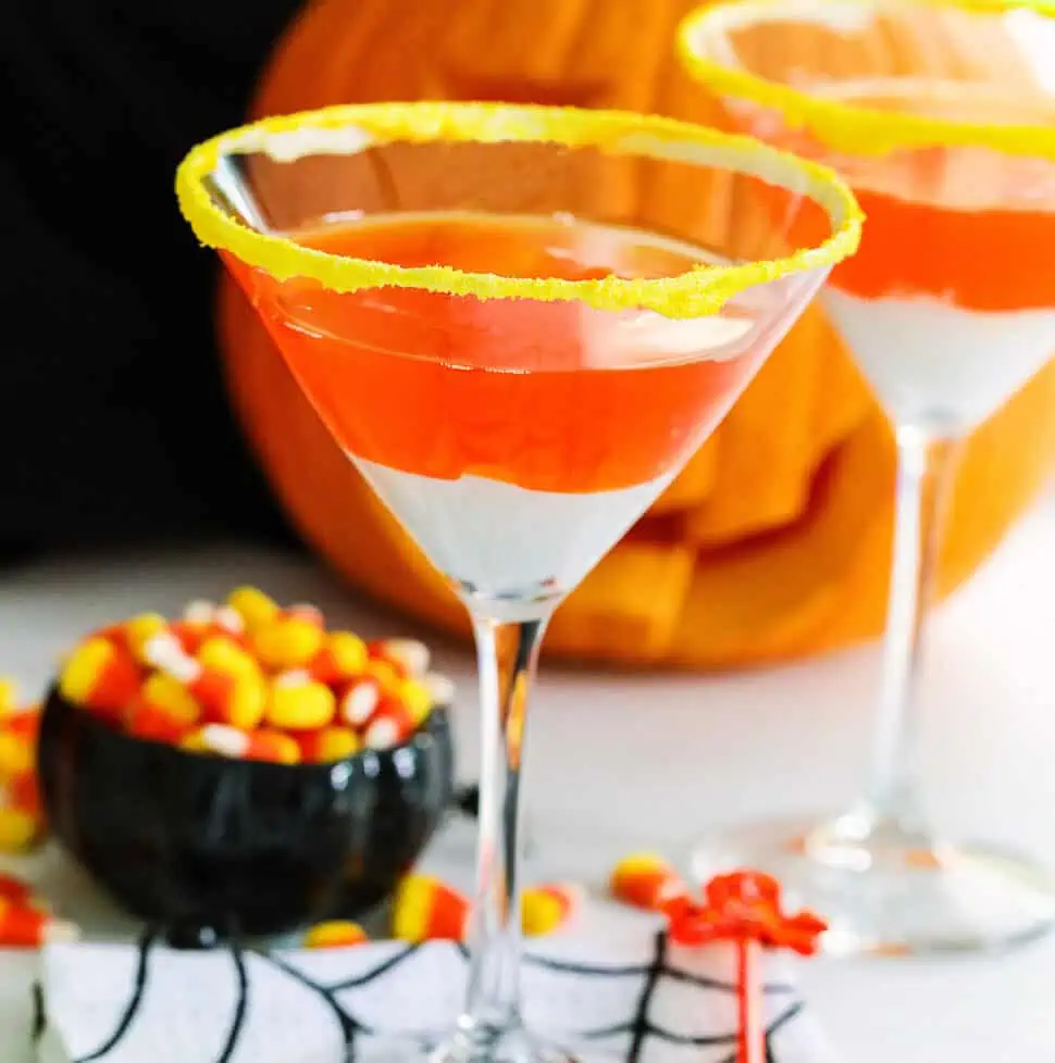 A Halloween party with candy corn martinis and a small black dish of candy corn nearby.