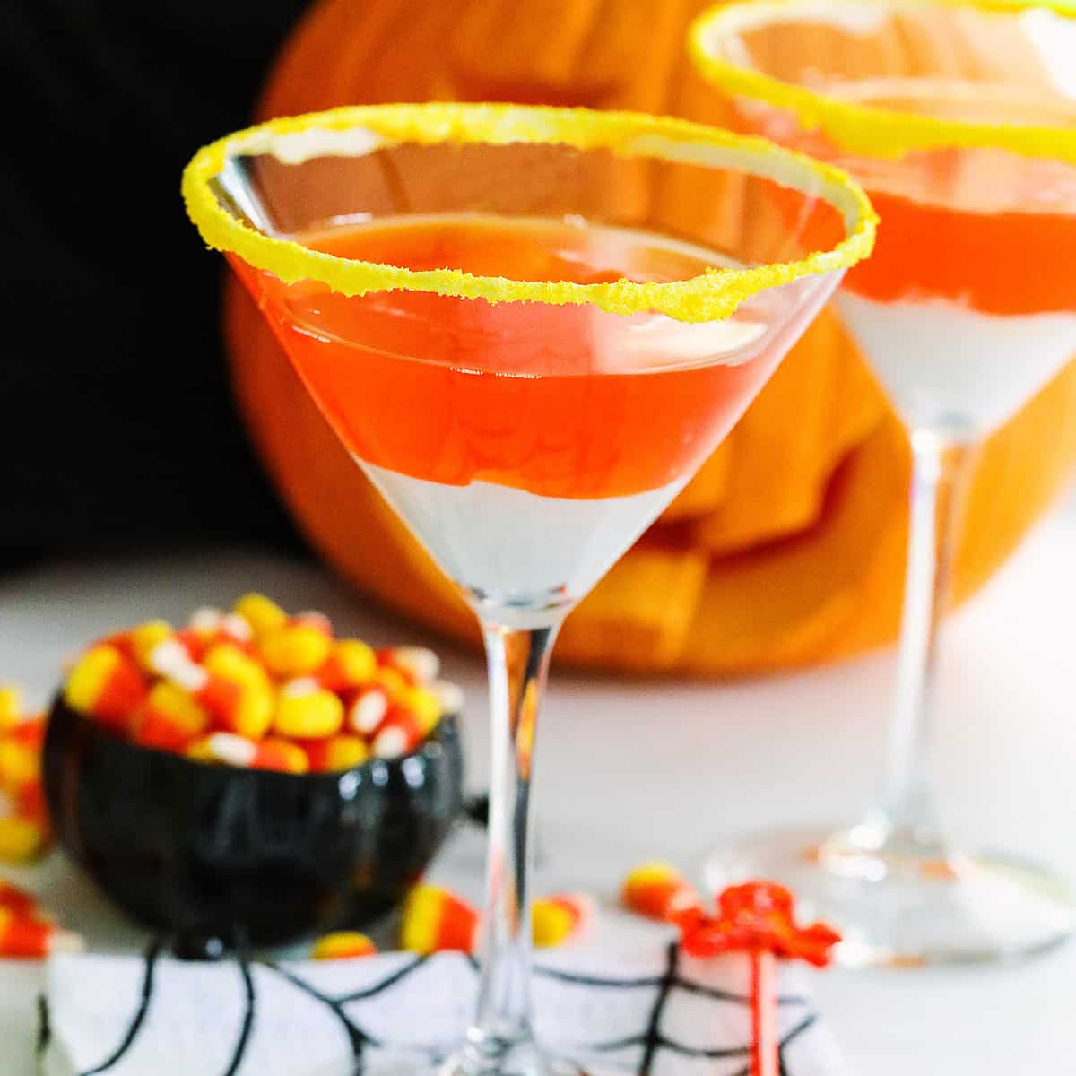 A Halloween party with candy corn martinis and a small black dish of candy corn nearby.