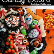 A Halloween candy board on a black tray loaded with cute candy for a party including pumpkins, licorice, mints, lollipops and gummy candy.