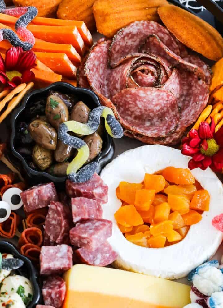 A large Halloween Charcuterie cheeseboard loaded with stacks of crackers, cut and sliced meats, nuts, and Halloween candy for a Halloween party.