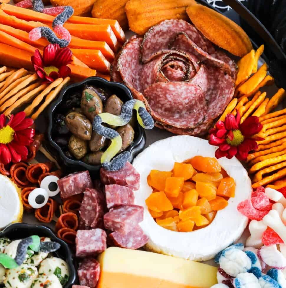 A large Halloween Charcuterie cheeseboard loaded with stacks of crackers, cut and sliced meats, nuts, and Halloween candy for a Halloween party.