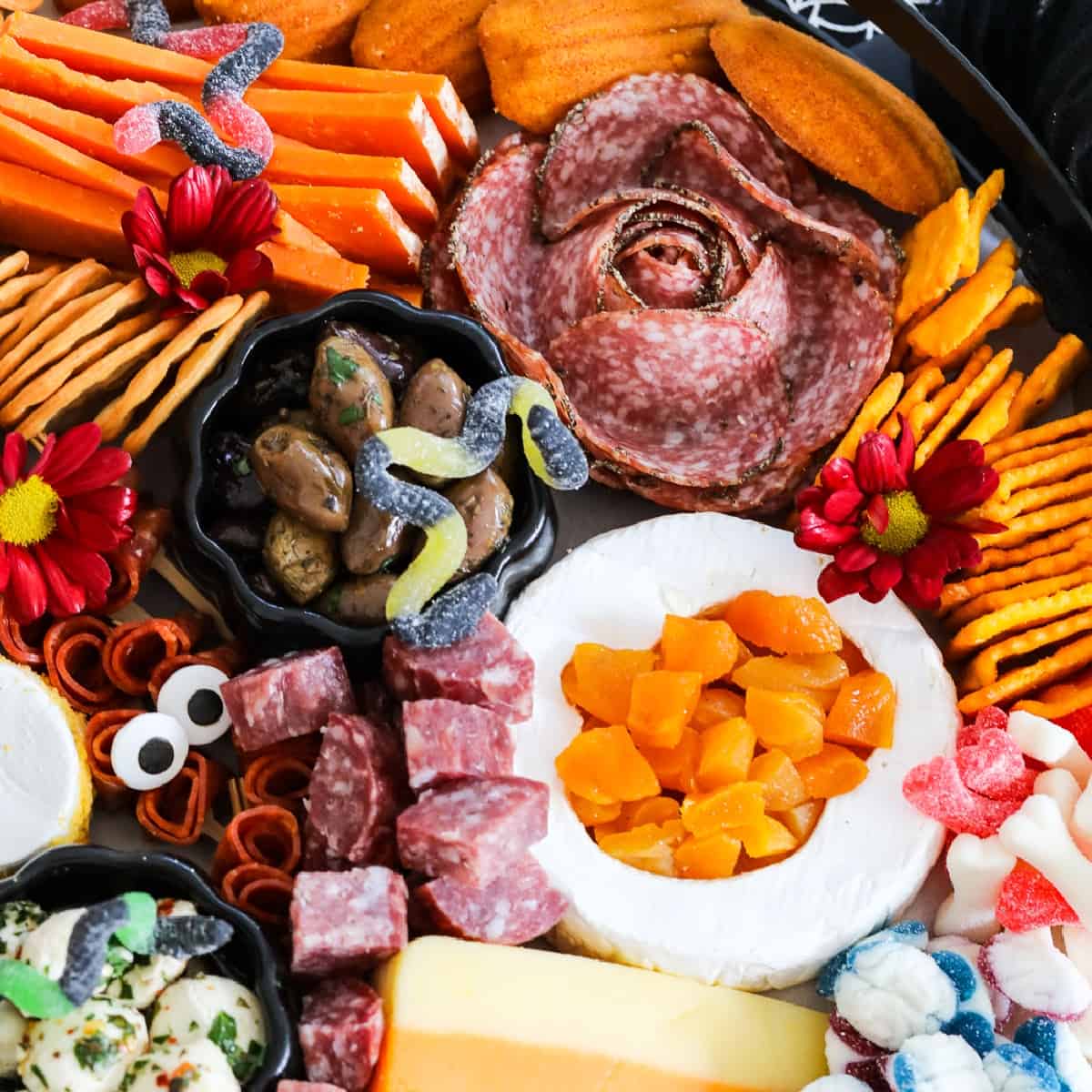 A large Halloween Charcuterie cheeseboard loaded with stacks of crackers, cut and sliced meats, nuts, and Halloween candy for a Halloween party.