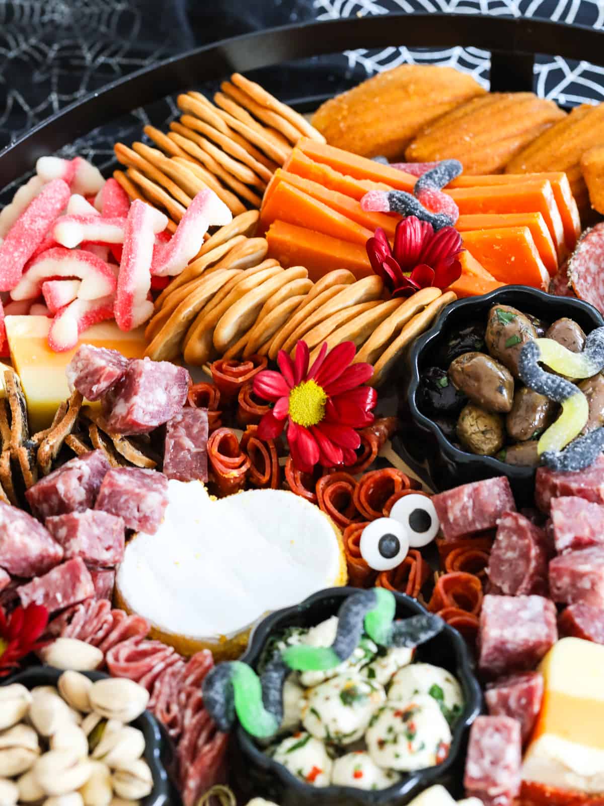 A large Halloween Charcuterie cheeseboard loaded with stacks of crackers, cut and sliced meats, nuts, and Halloween candy for a Halloween party.