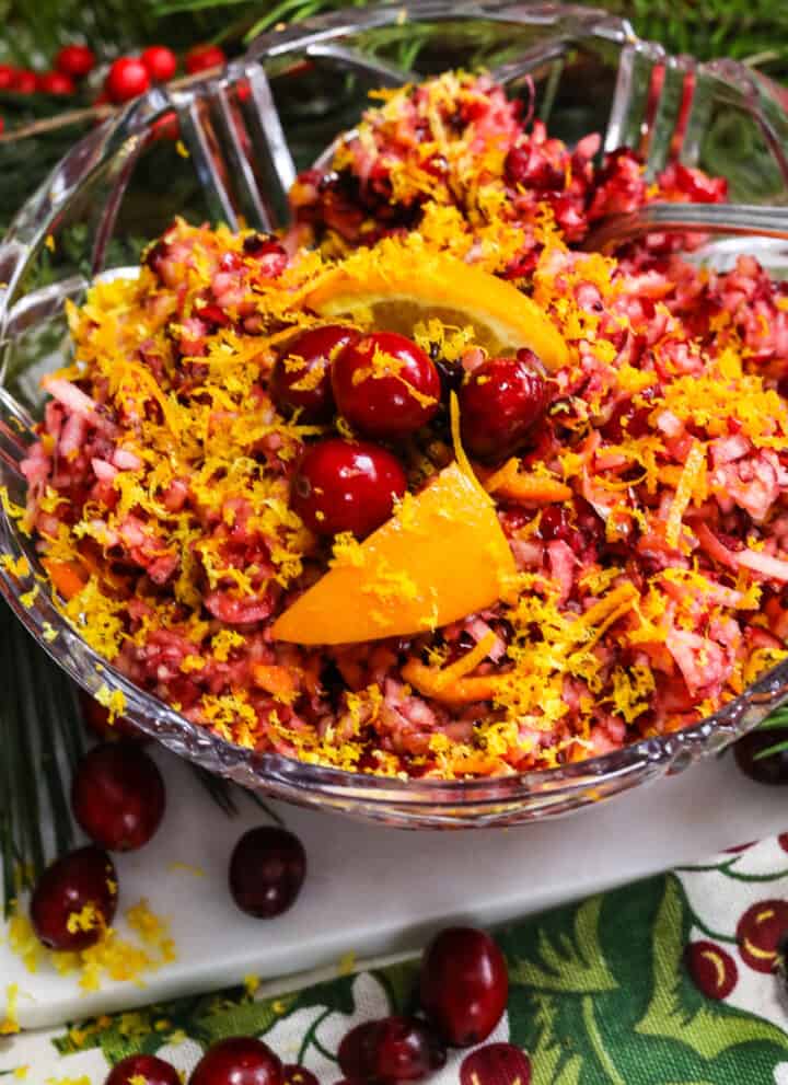 A gorgeous red and orange cranberry relish in a clear crystal bowl with a spoon.