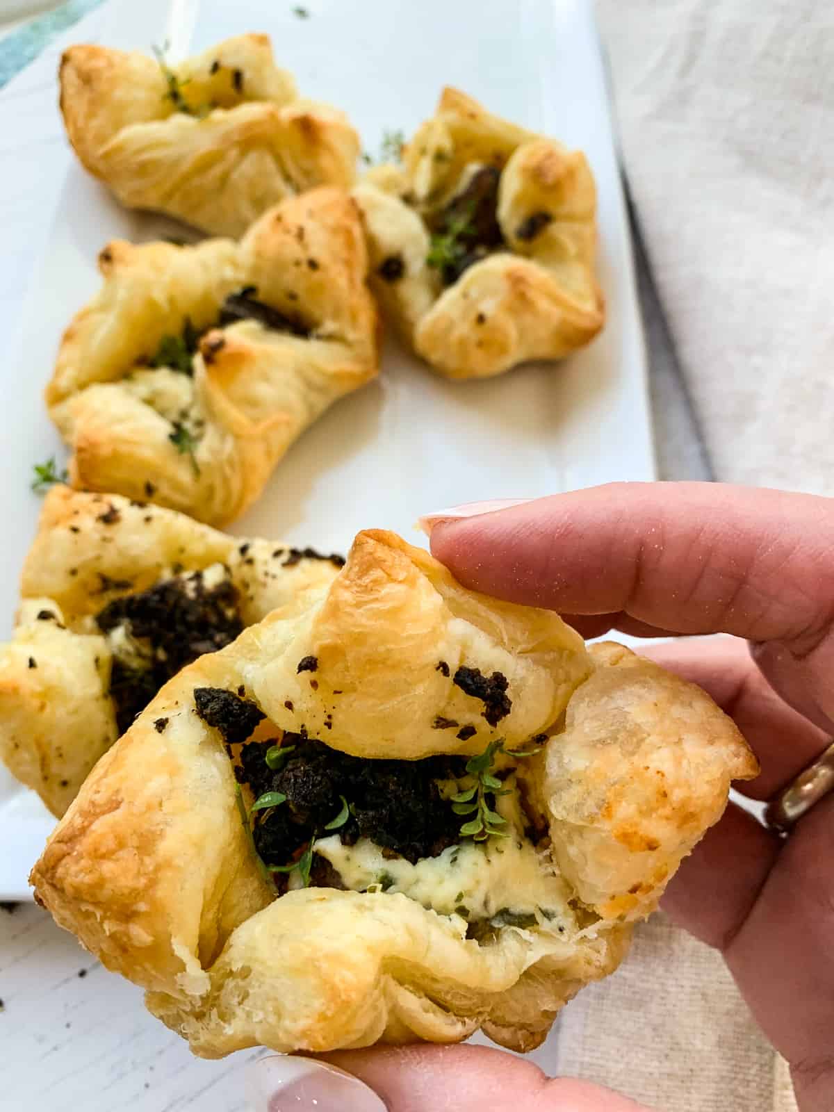 Lady holding a freshly baked beef wellington appetizer made from puff pastry.