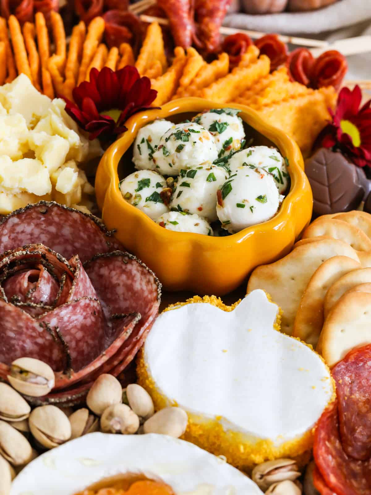 Close up of marinated mozzarella balls in a yellow dish on a Thanksgiving charcuterie board.