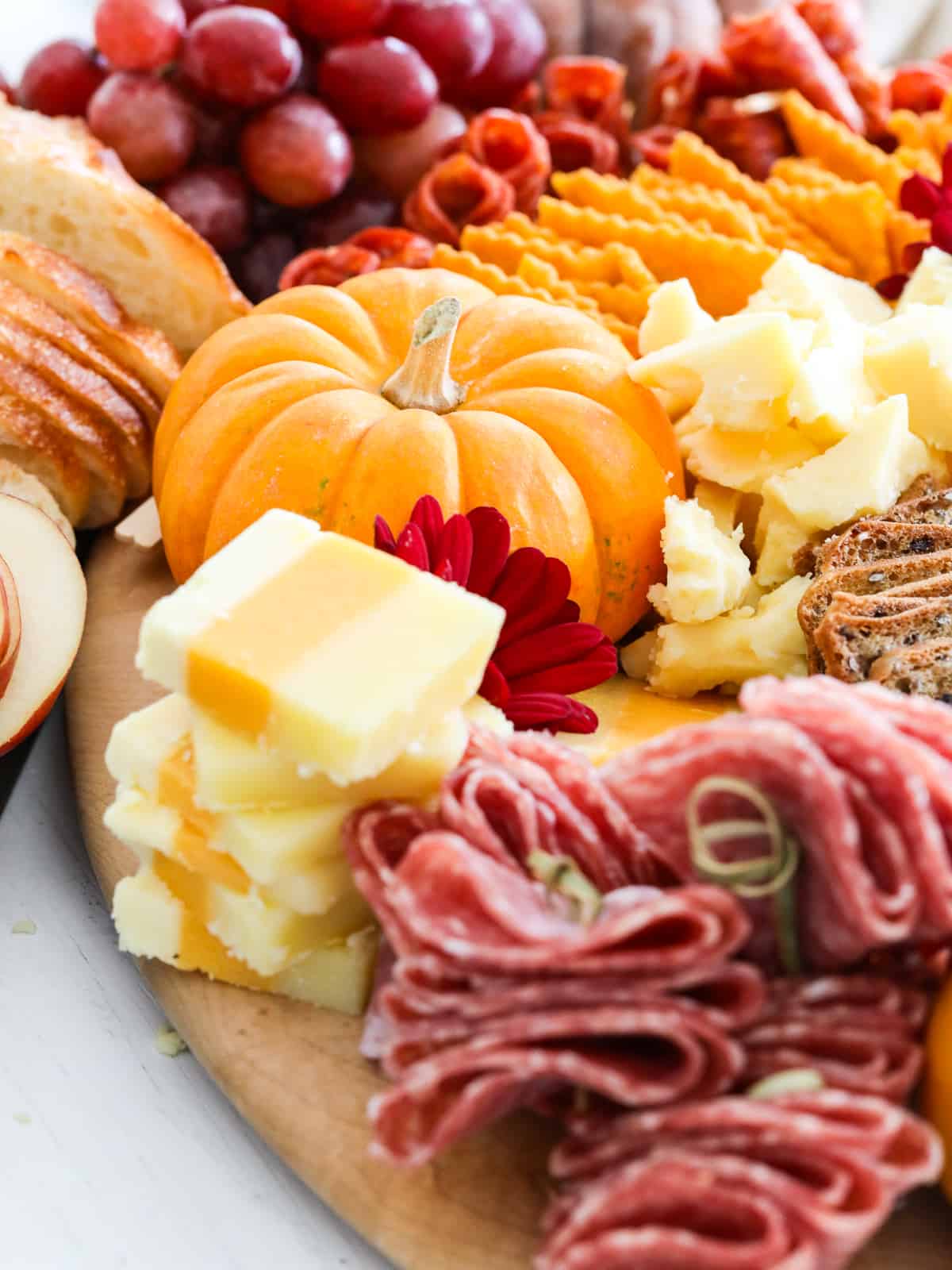 A charcuterie board filled with different colors and shapes of cheeses for a Fall appetizer board. 