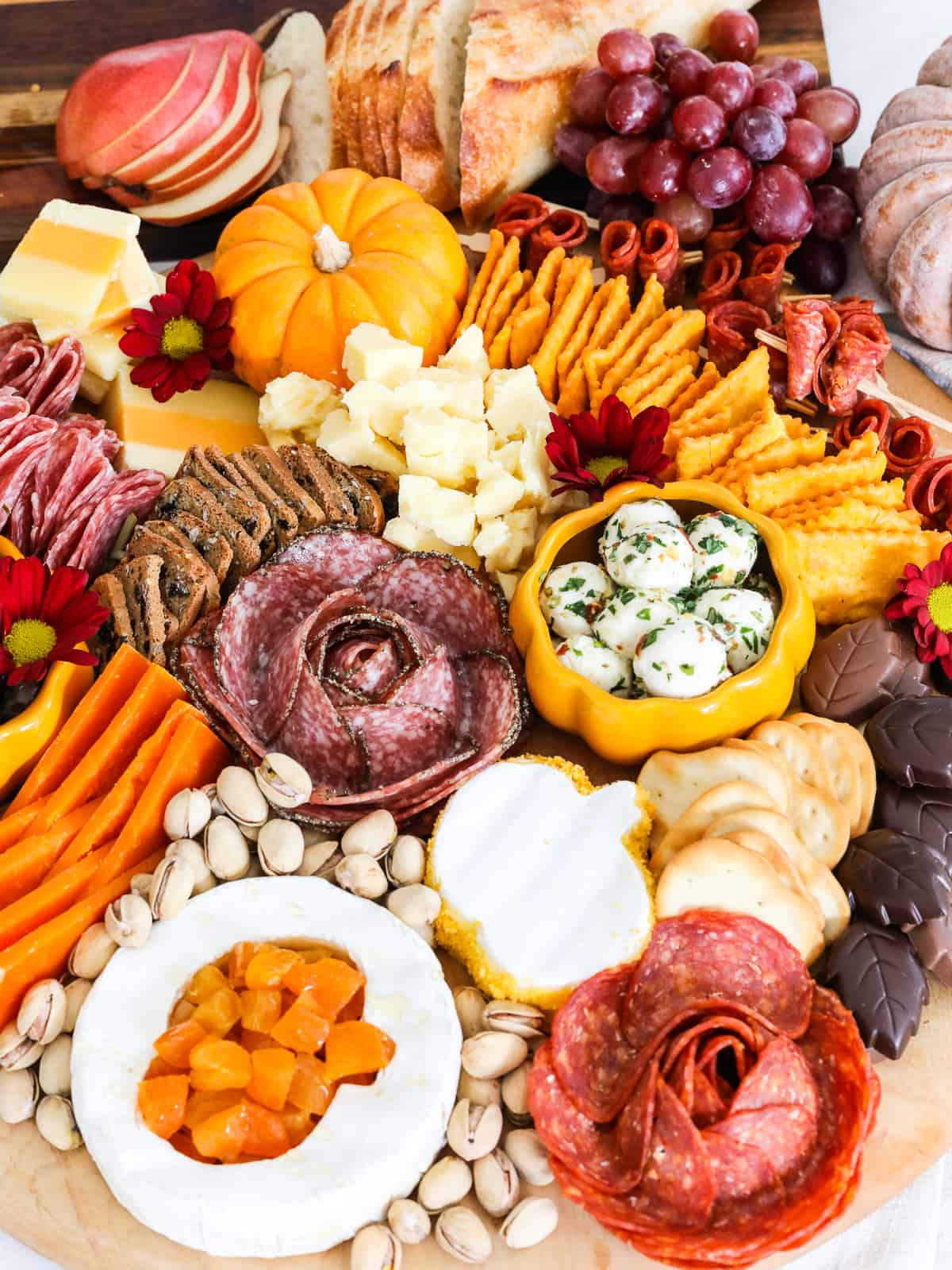 Looking down on a Thanksgiving charcuterie board filled with Fall colored cheeses, sliced meats, fruit, nuts, chocolates, crackers and more. 
