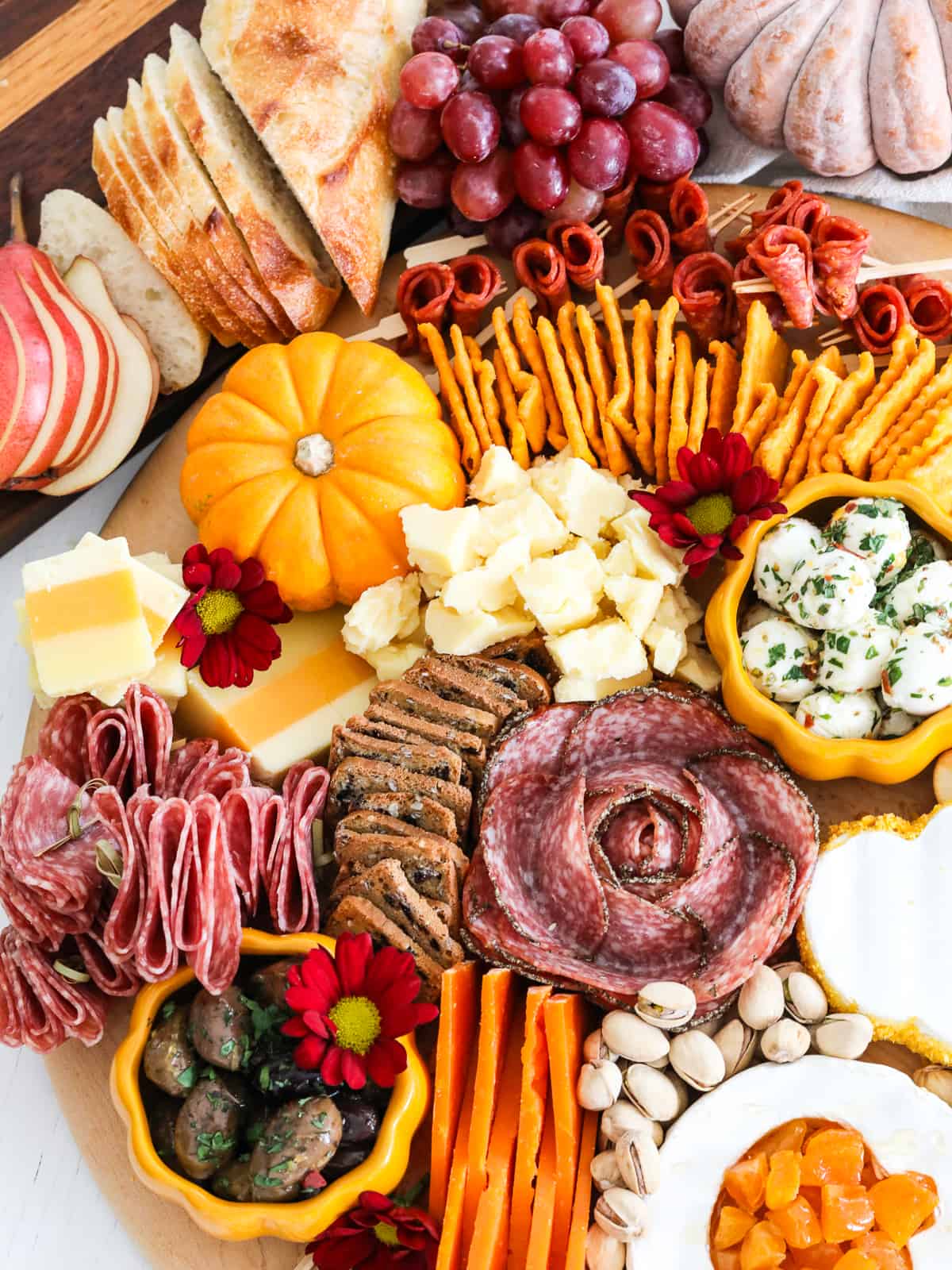 A gorgeous Thanksgiving charcuterie board filled with gourmet cheeses, sliced meats, nuts, fruit, crackers, and sliced bread. 