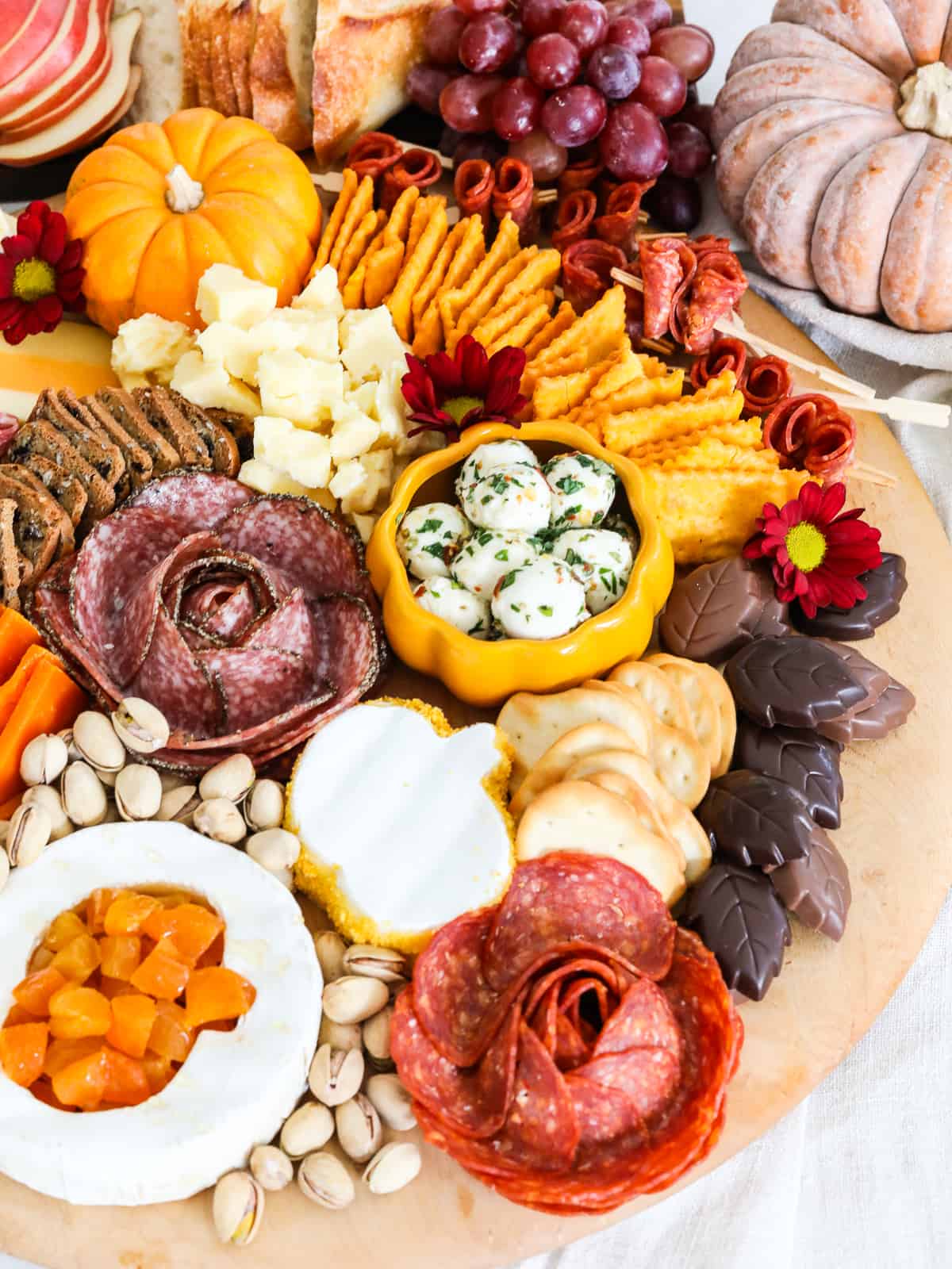 A round cheeseboard loaded with Thanksgiving charcuterie cheeses, meats, nuts, fruit and more. 