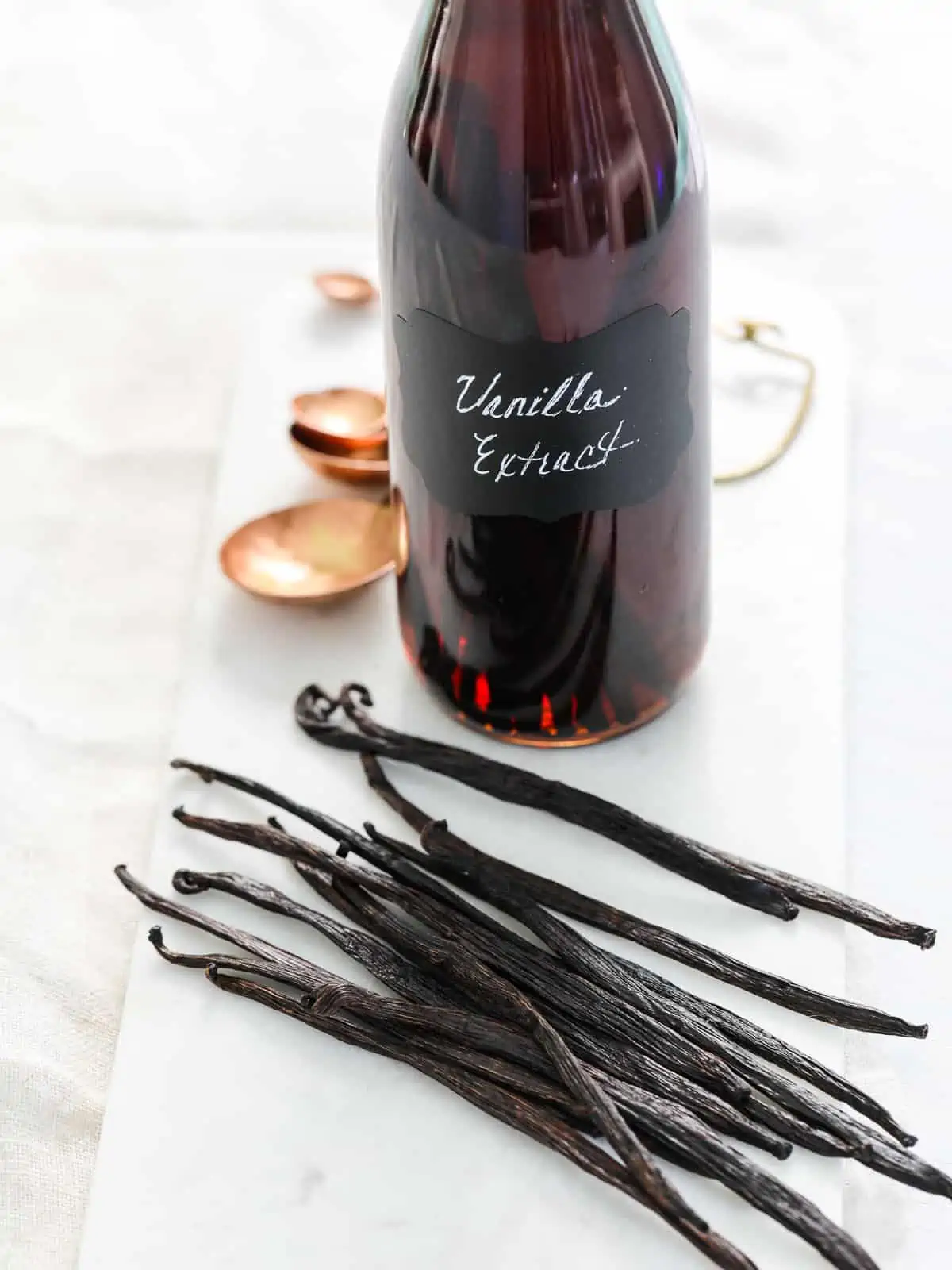 A glass bottle with a label that says vanilla extract and you can see vanilla beans in the bottle.