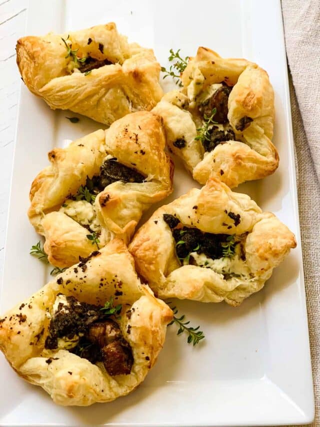 Five golden brown beef wellington appetizers on a white platter and a beige linen towel baked hot out of the oven ready to eat.