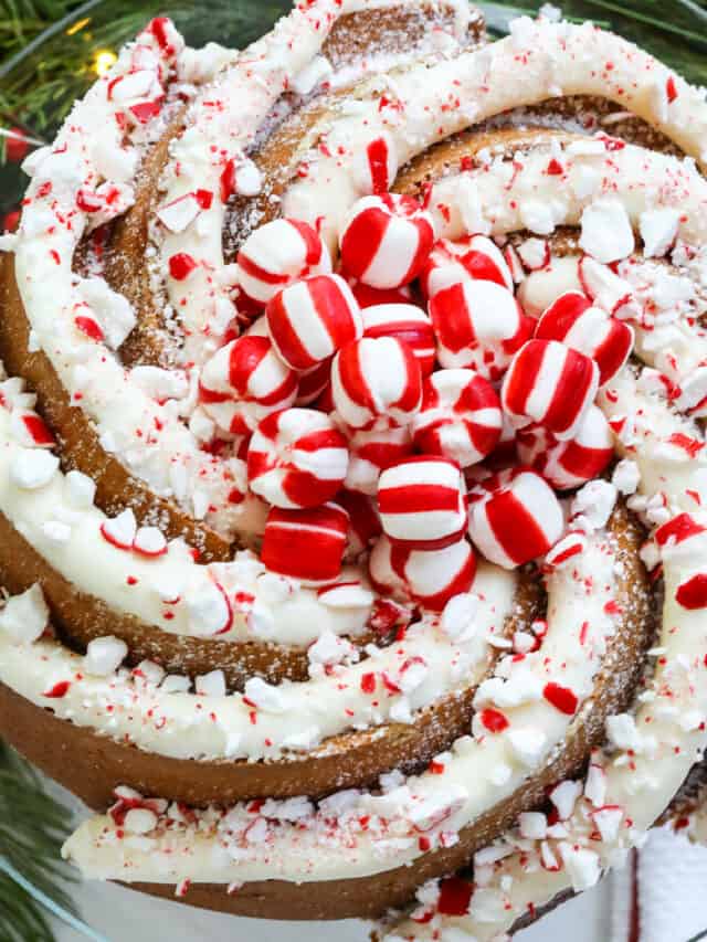A gorgeous swirl bundt Christmas cake decorated with large piping of peppermint buttercream frosting and crushed and whole candy cane peppermints.