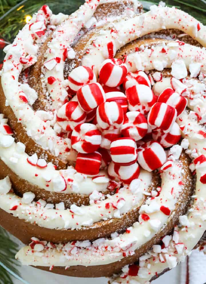 A gorgeous swirl bundt Christmas cake decorated with large piping of peppermint buttercream frosting and crushed and whole candy cane peppermints.