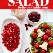 A white plate with green salad topped with red raspberries and white trees for Christmas.