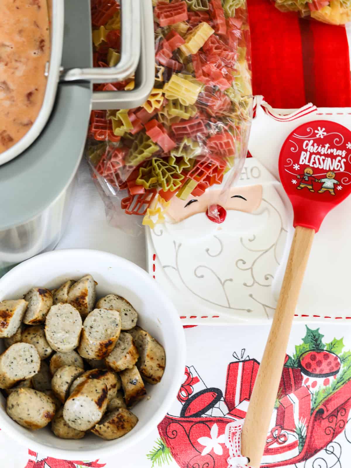 A white bowl filled with sliced chicken sausage and a bag of holiday pasta, to make soup. 