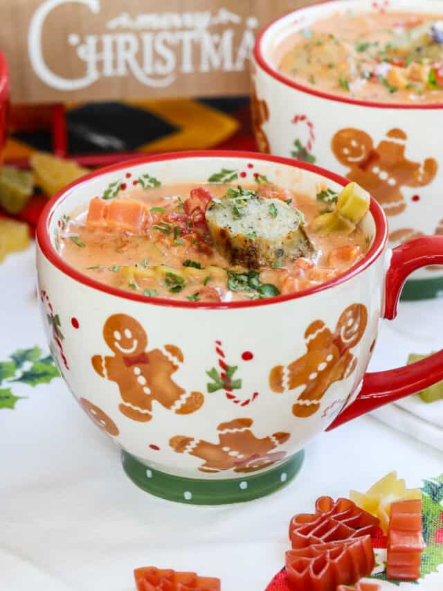 A cheerful red handled holiday mug with gingerbread filled with Christmas soup.