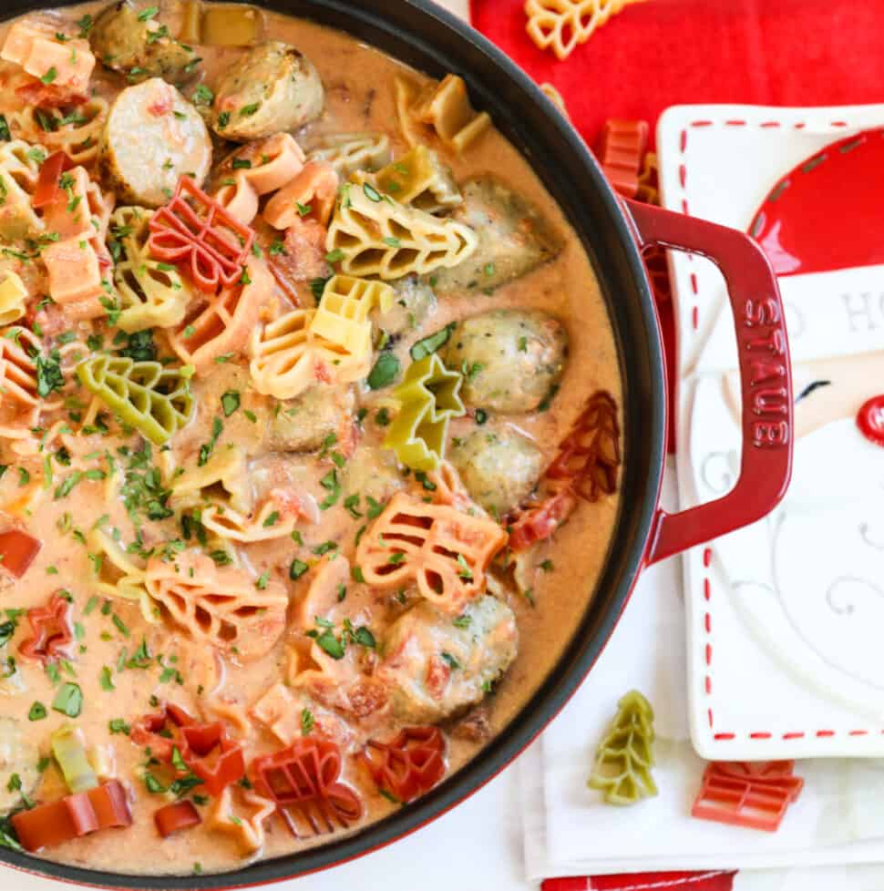 A large red cast iron pot filled with Christmas soup topped with holiday pasta.