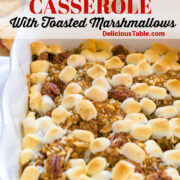 White casserole dish with sweet potato casserole topped with golden brown mini marshmallows.