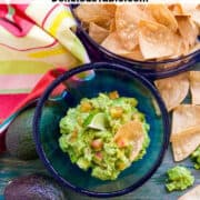 Looking down on a bowl of guacamole and tortilla chips with a bright color towel.