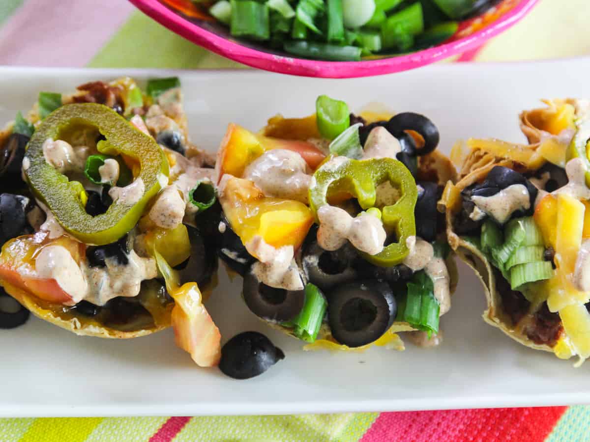 3 Mini Tacos topped with jalapenos, refried beans, tomatoes and black olives.