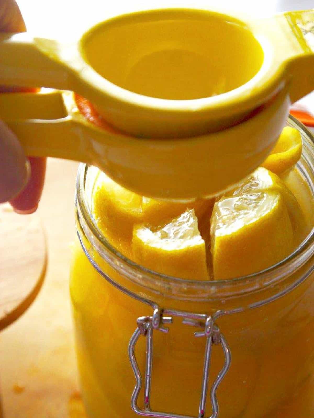 Using a lemon juicer to add lemon juice into the clamp jar. 