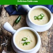 Looking down on two bowls of jalapeno popper soup topped with grated cheese and thin sliced jalapenos.