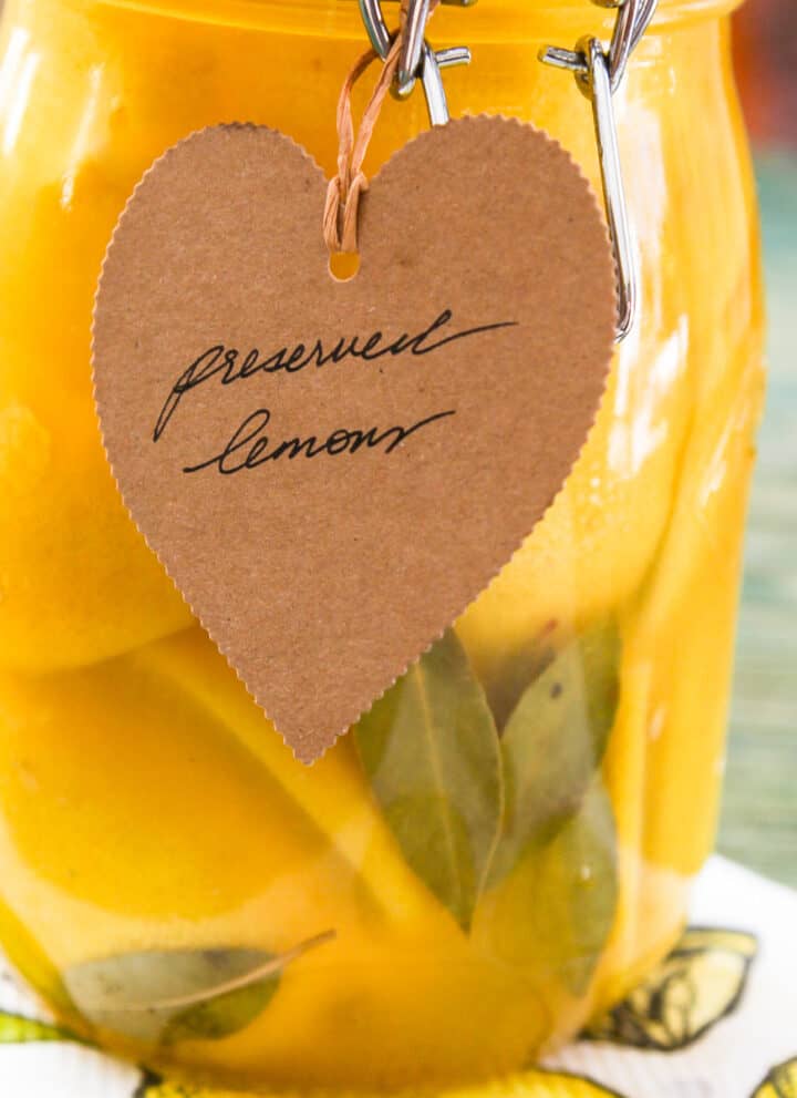 A large clamp jar of Preserved Lemons with a brown craft paper tag that says Preserved Lemons.