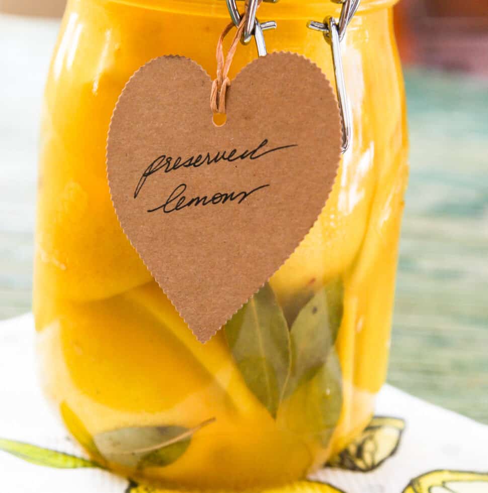 A large clamp jar of Preserved Lemons with a brown craft paper tag that says Preserved Lemons.