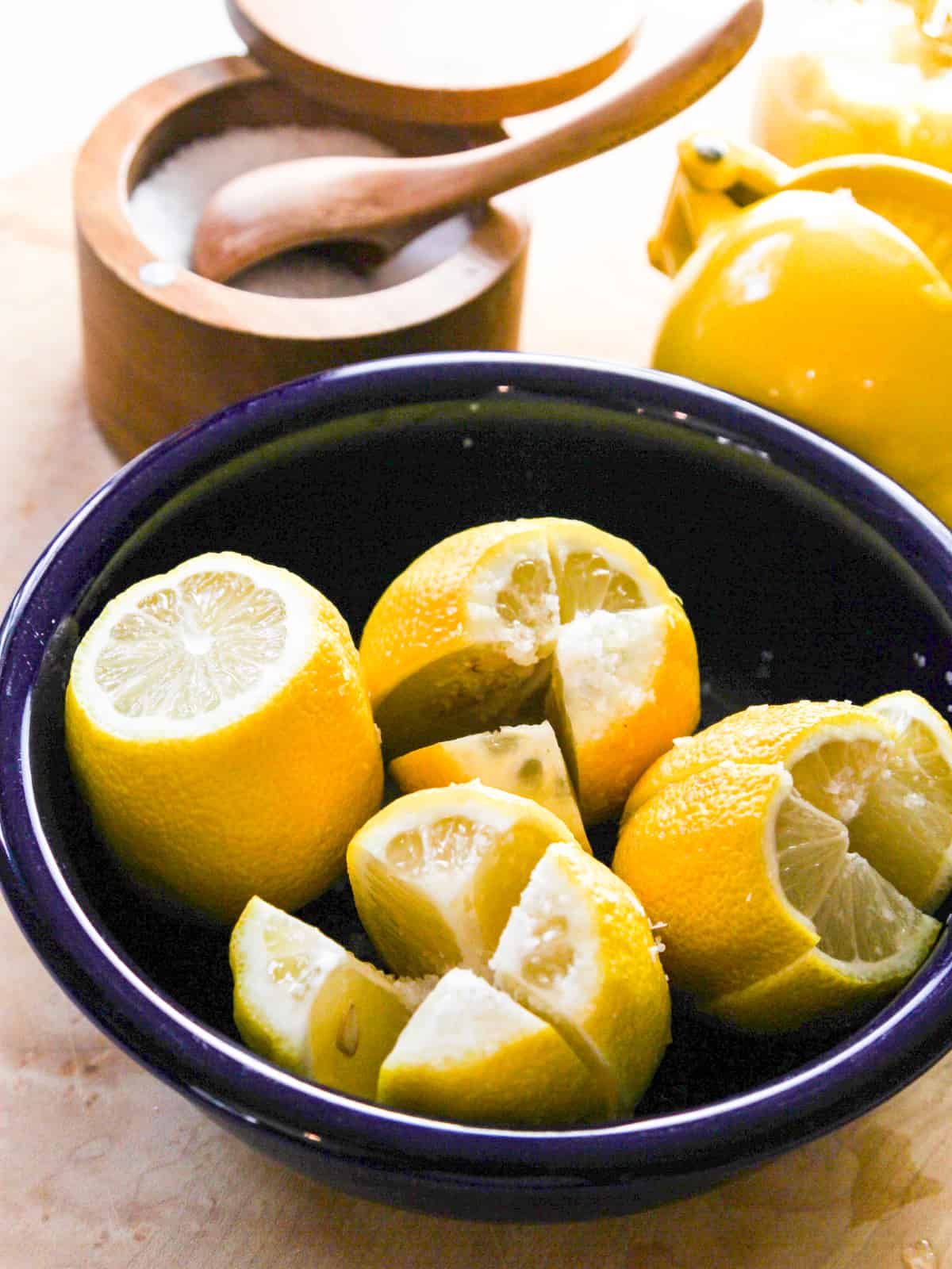 Cut lemons in a blue bowl sliced and salted to make preserved lemons. 