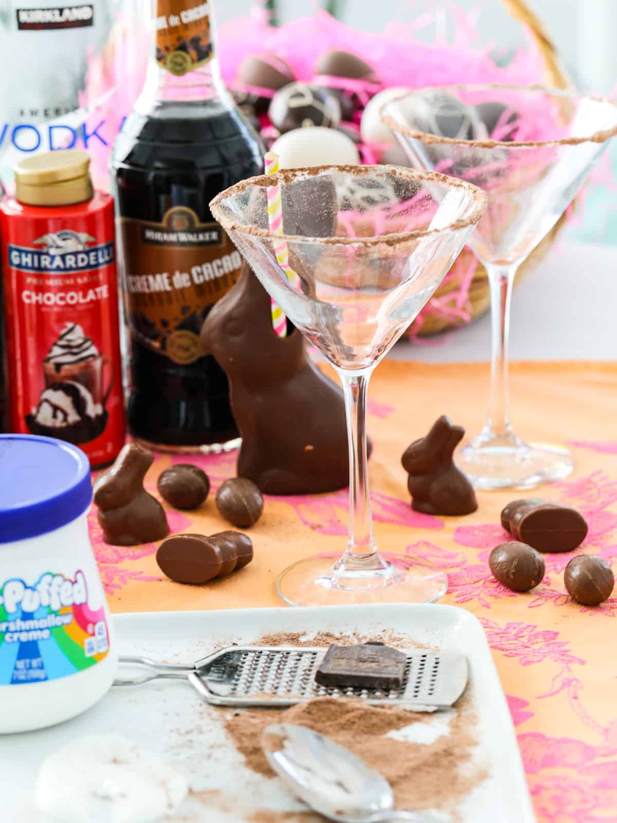 A martini glass with the edge rimmed in chocolate shavings and ingredients to make chocolate martinis.