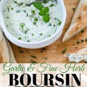 A white bowl filled with herb cream cheese and small baguettes sliced to spread it on.