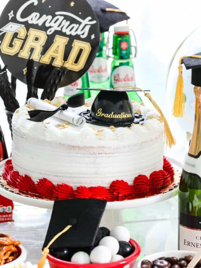 A grad party with red, white, and black food themed items on a table like a cake and snacks.